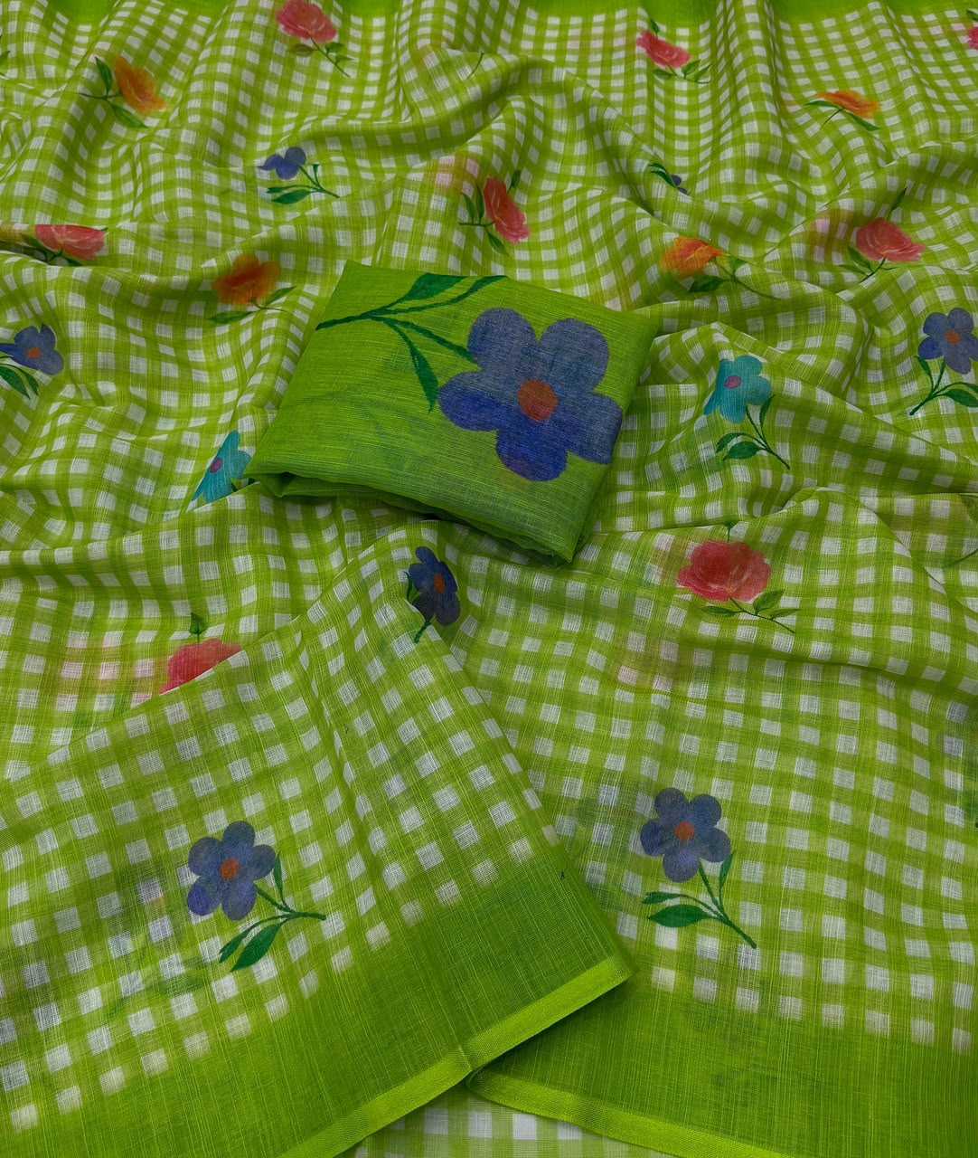 A lime green checkered saree with scattered floral prints in blue, pink, and teal, featuring a matching solid green fabric band.