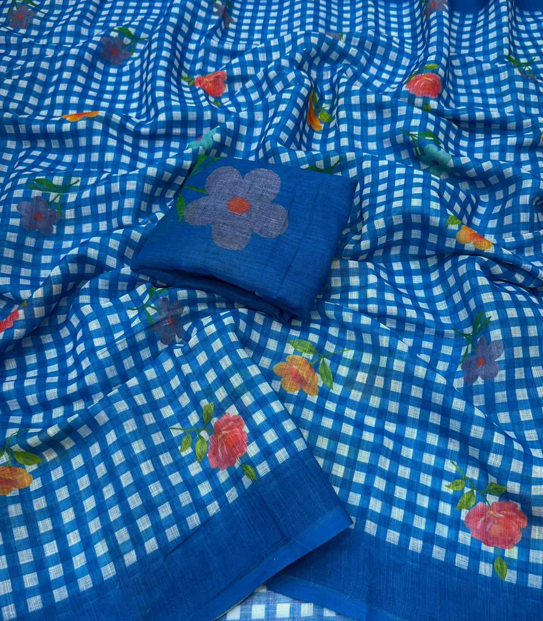 Blue and white checkered saree fabric with scattered floral prints in pink, orange, and green, featuring a matching blue fabric piece with a large embroidered flower.