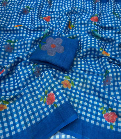 Blue and white checkered saree fabric with scattered floral prints in pink, orange, and green, featuring a matching blue fabric piece with a large embroidered flower.