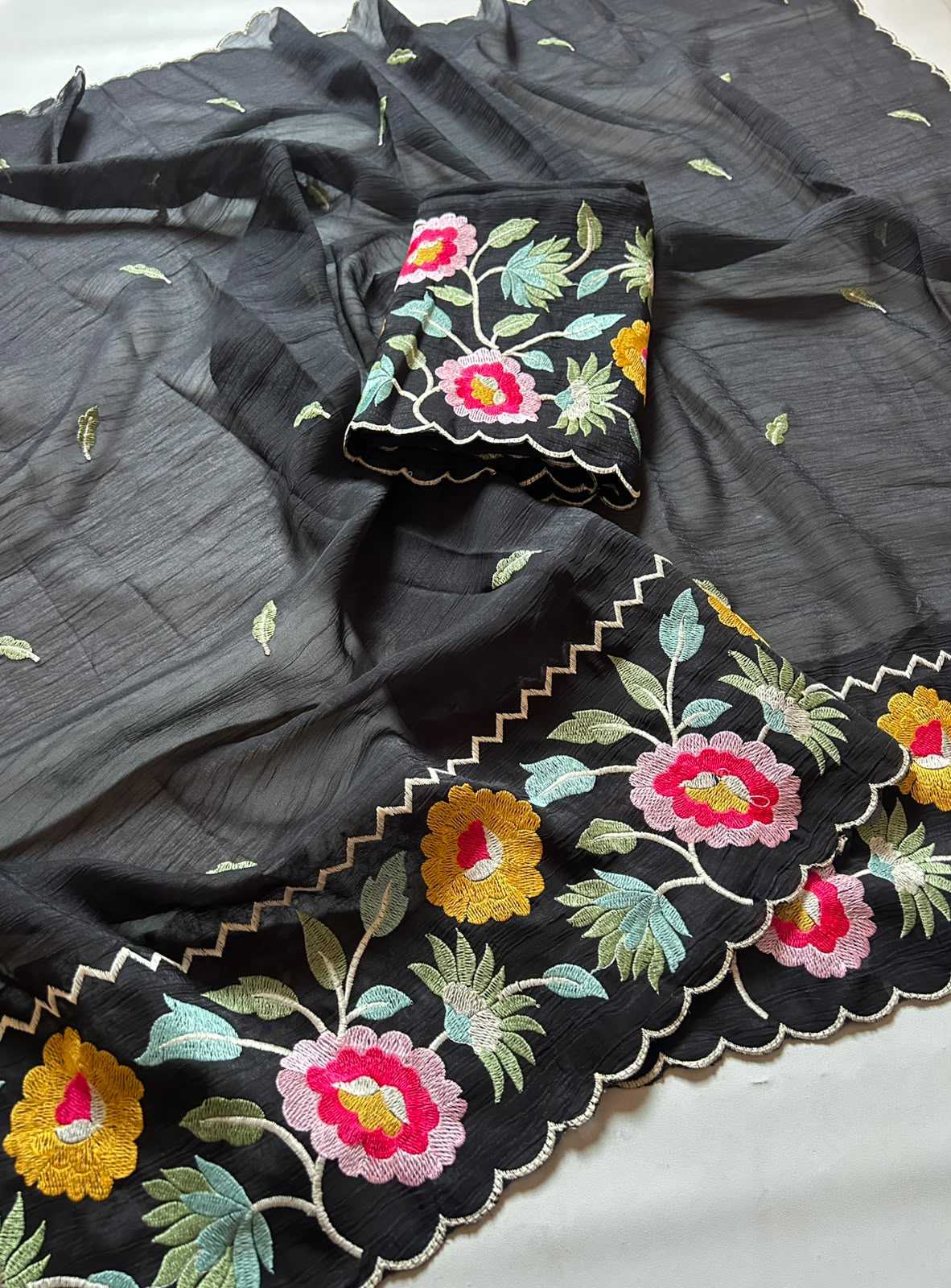 Black embroidered fabric with colorful floral patterns on a gray background