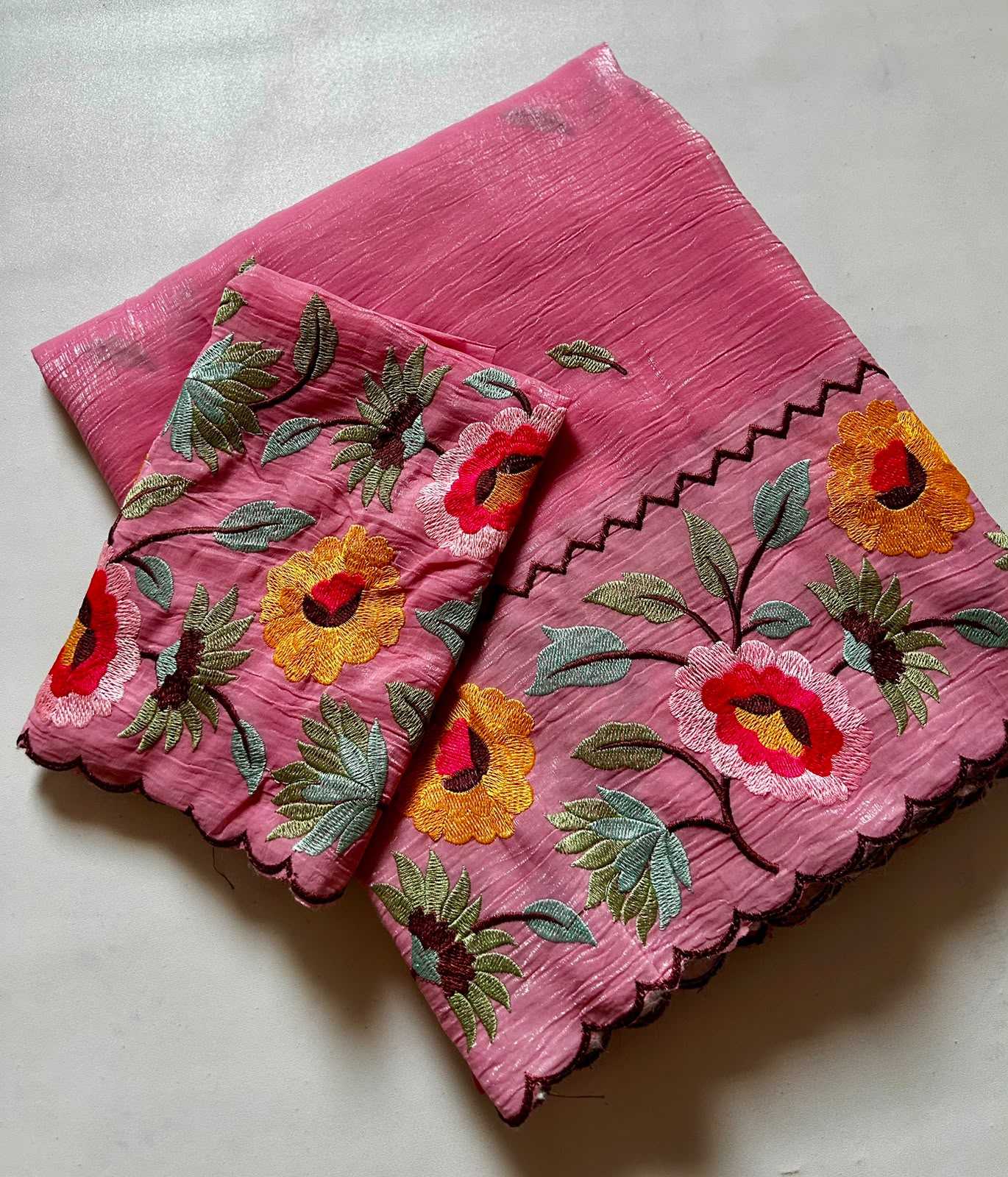 Pink fabric with floral embroidery on a light gray background