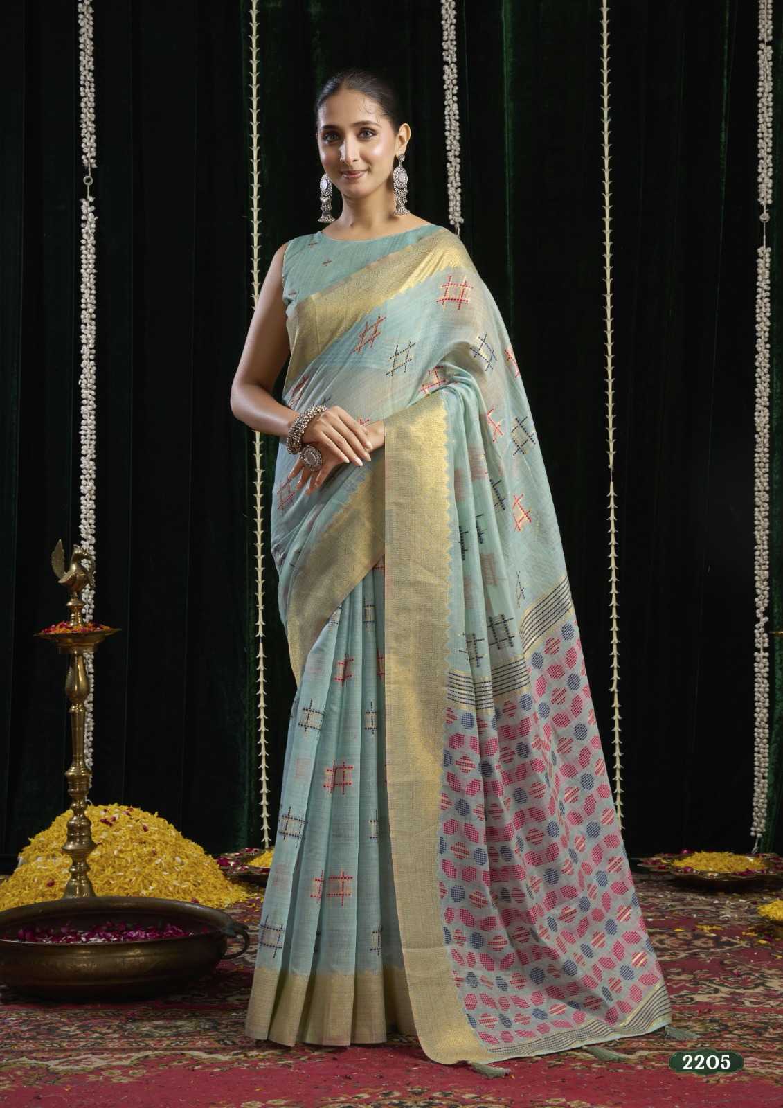 Woman wearing a light blue saree with a patterned border against a dark background