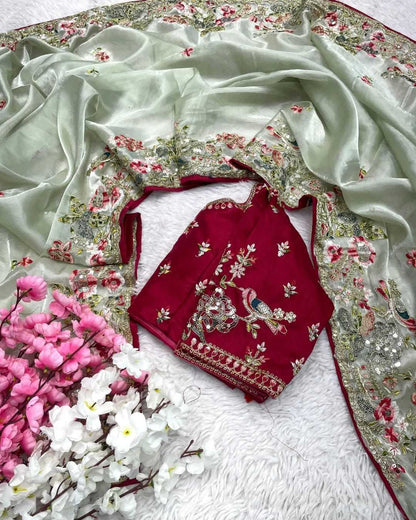 Embroidered red blouse with floral patterns on a white saree with floral border, surrounded by flowers.