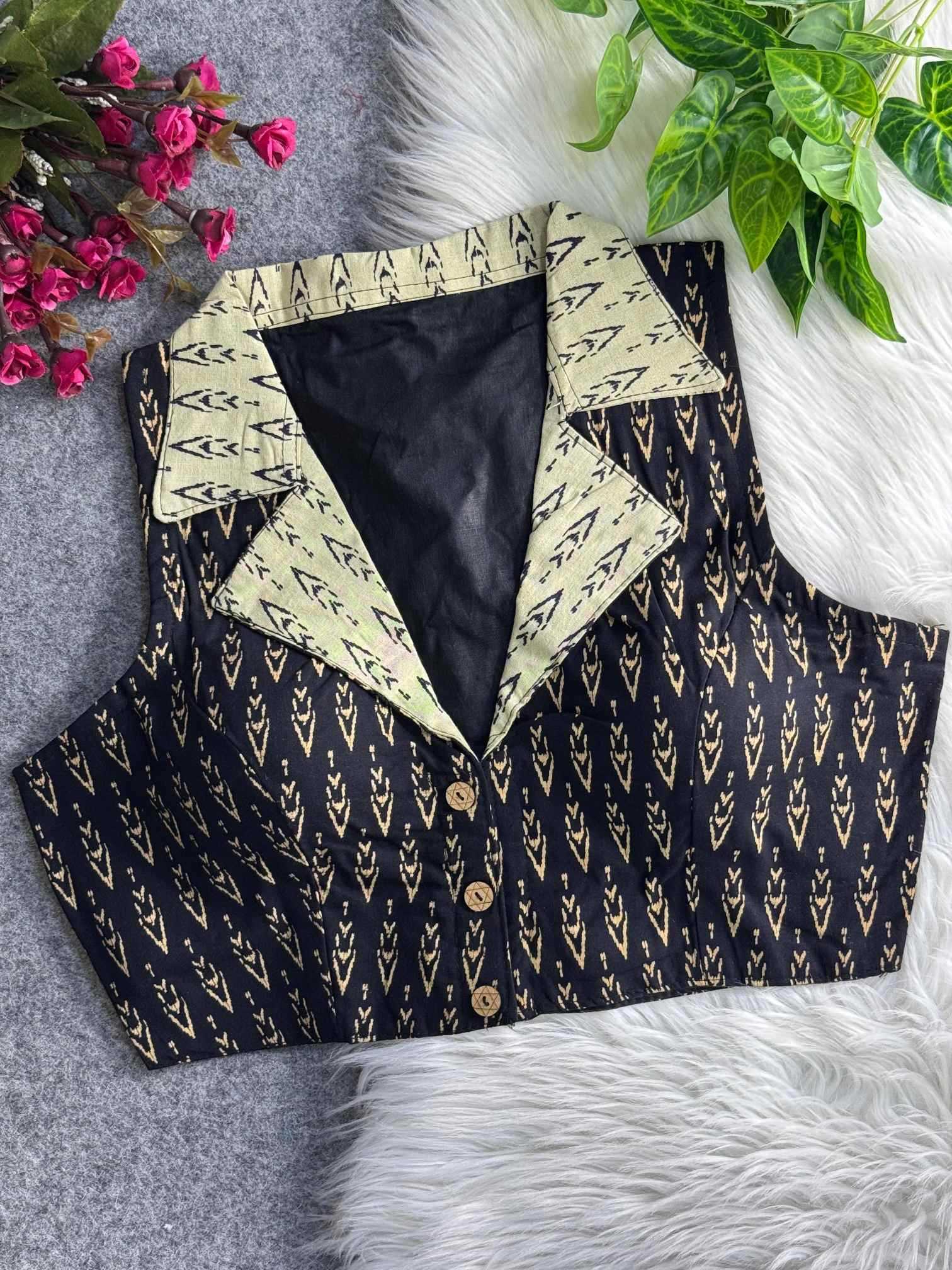 Black patterned vest with cream collar on a textured surface with flowers and leaves.