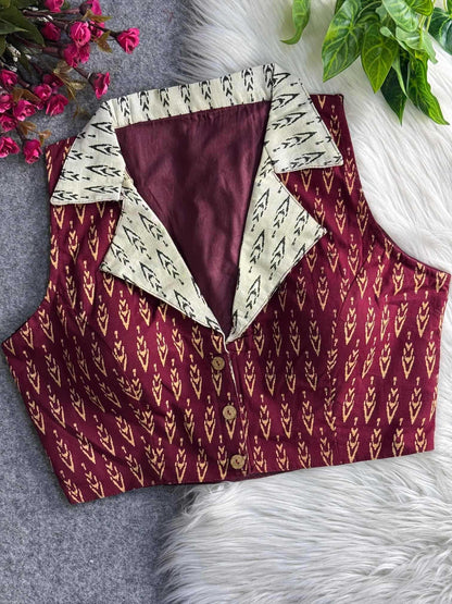 Maroon patterned blouse with white collar on a textured surface with flowers and leaves.