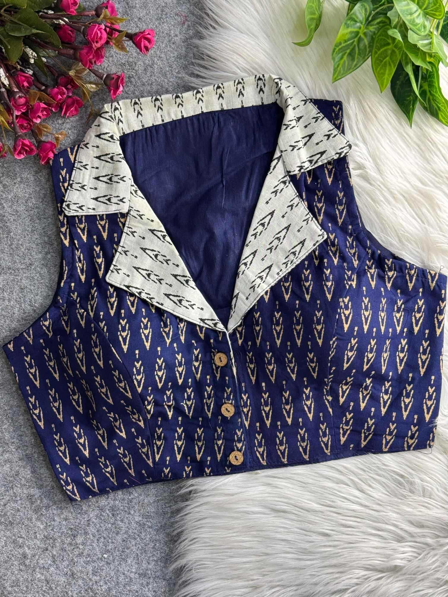 Blue patterned shirt with white collar on a textured surface with flowers and leaves.