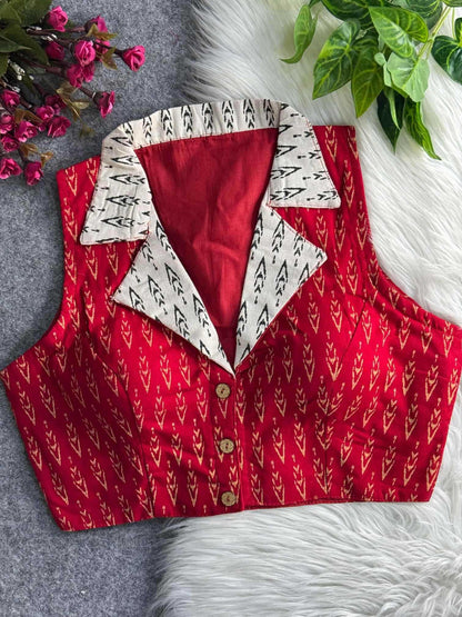 Red patterned vest with white collar on a textured surface with flowers and leaves.