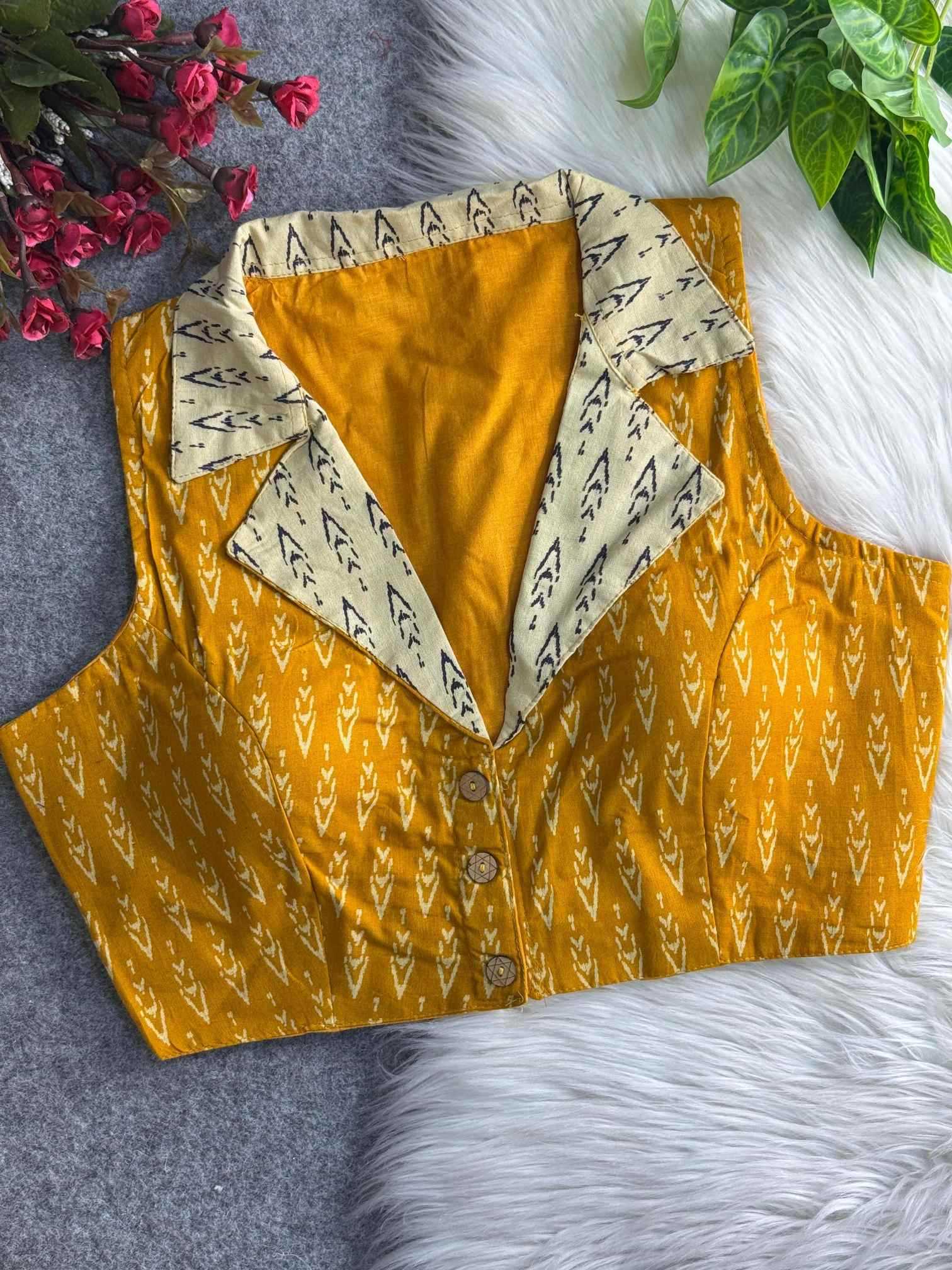 Yellow patterned shirt with a white collar on a textured surface with flowers and leaves.