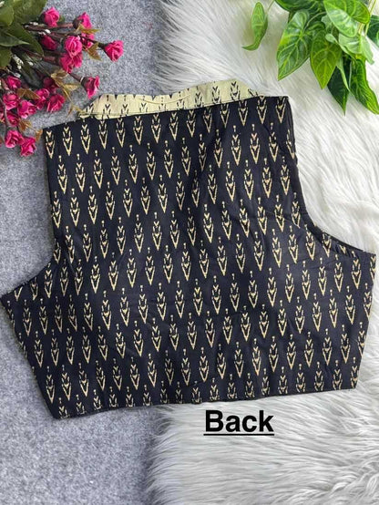 Black top with gold pattern on a textured surface with flowers and leaves.