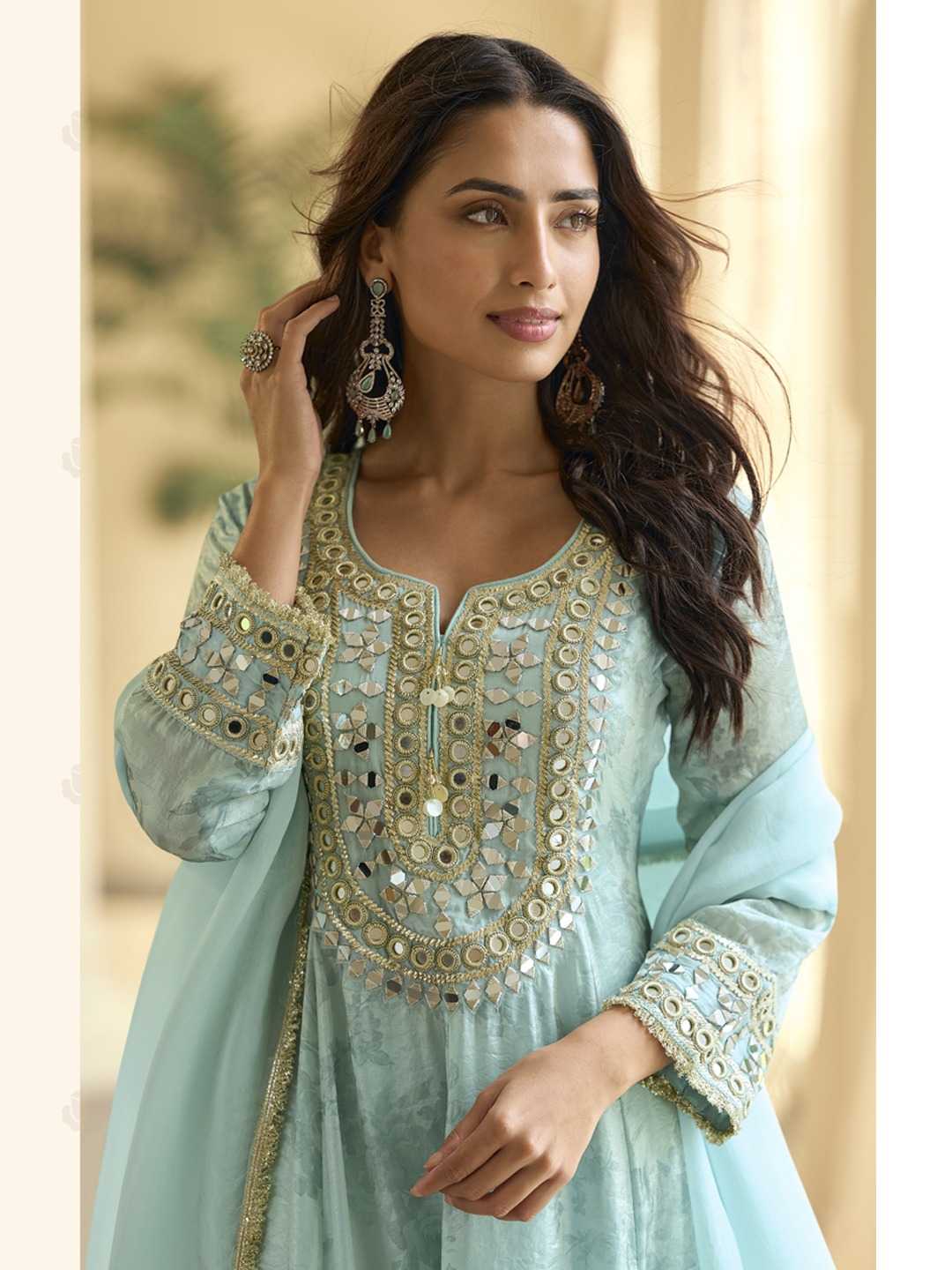 Woman wearing a light blue embroidered traditional outfit with gold details.