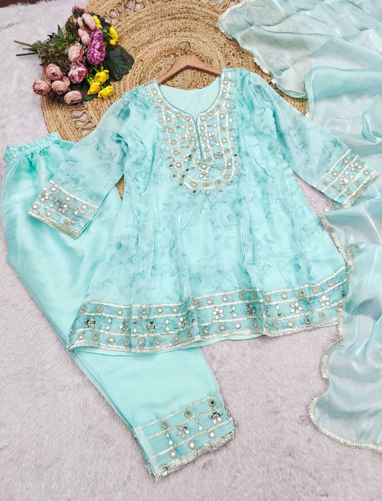 Light blue embroidered outfit with a hat and flowers on a textured surface