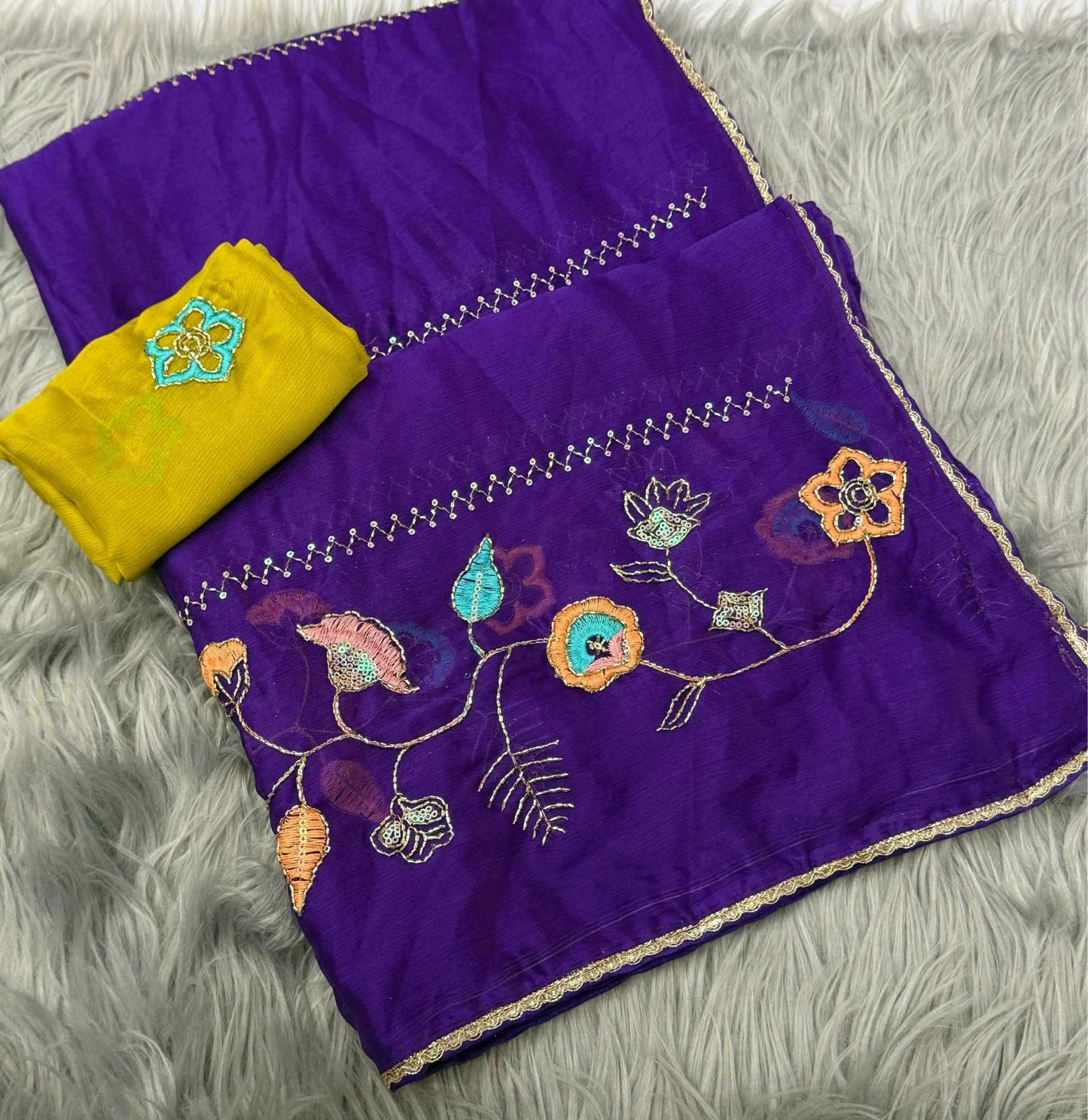 Purple embroidered fabric set with a matching yellow cloth, laid flat on a gray faux fur background. The purple fabric features multicolor floral embroidery and silver mirror work borders.