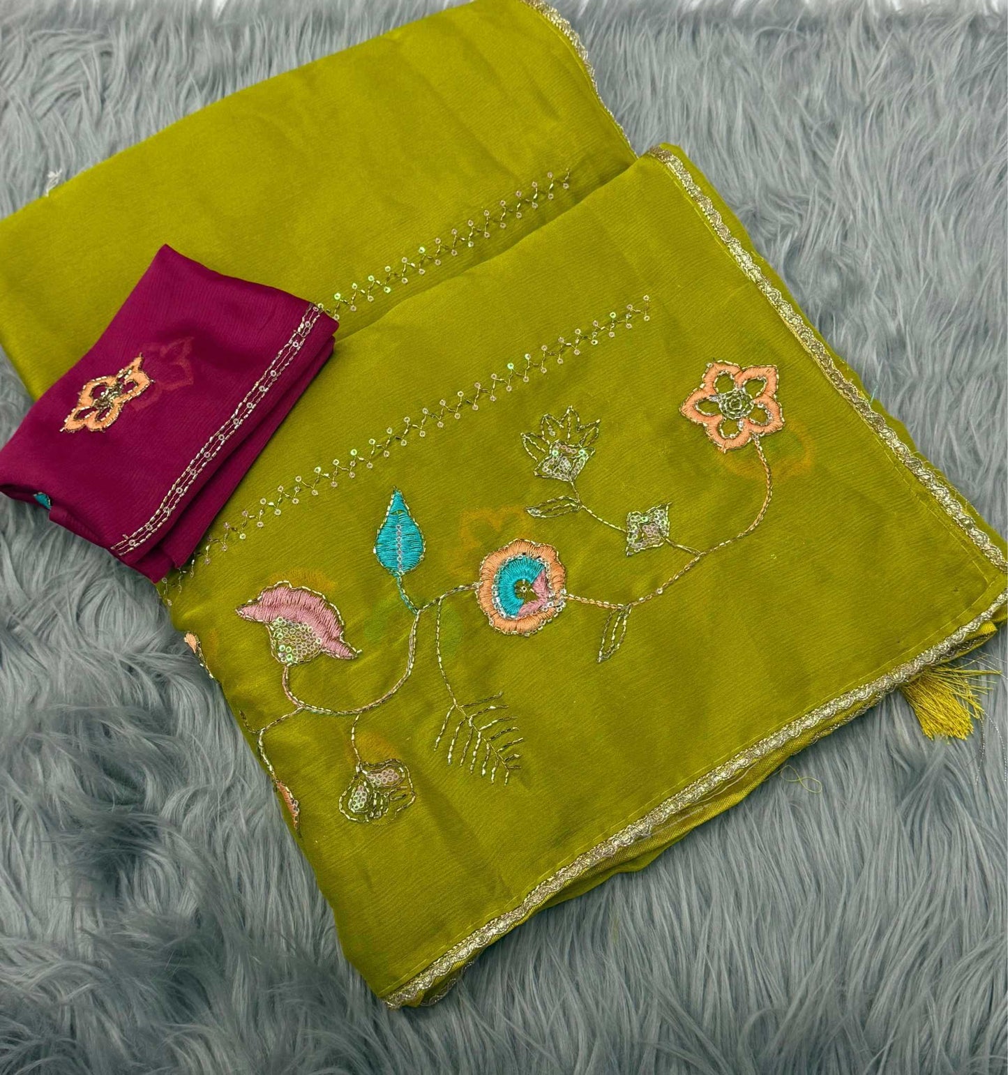 Green embroidered fabric with a purple item on a gray textured surface