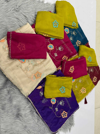 A set of folded embroidered fabric pieces in multiple colors, including purple, magenta, blue, and olive green, arranged on a gray faux fur surface.