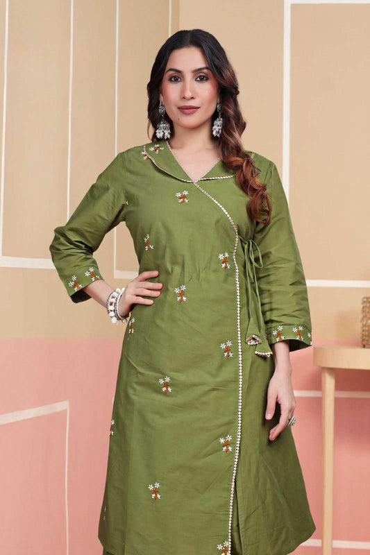 Woman wearing a green traditional outfit with floral patterns on a beige and pink background