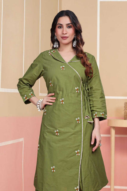 Woman wearing a green traditional outfit with floral patterns on a beige and pink background