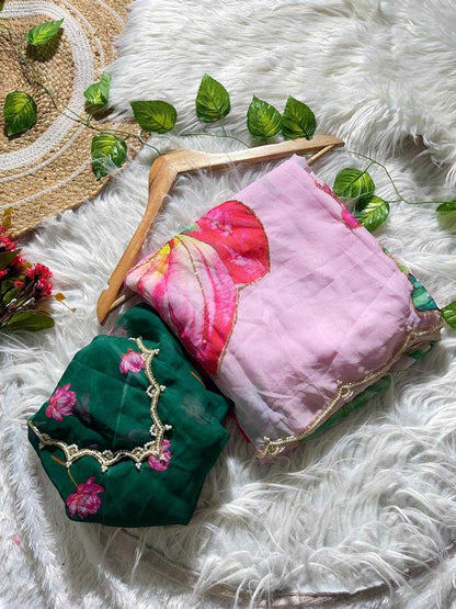 Two folded fabric items, likely scarves or small bags, displayed on a white faux-fur surface with decorative leaves and a woven mat. One item is dark green with pink floral print and gold embroidery, and the other is light pink with a large red floral print and gold trim.