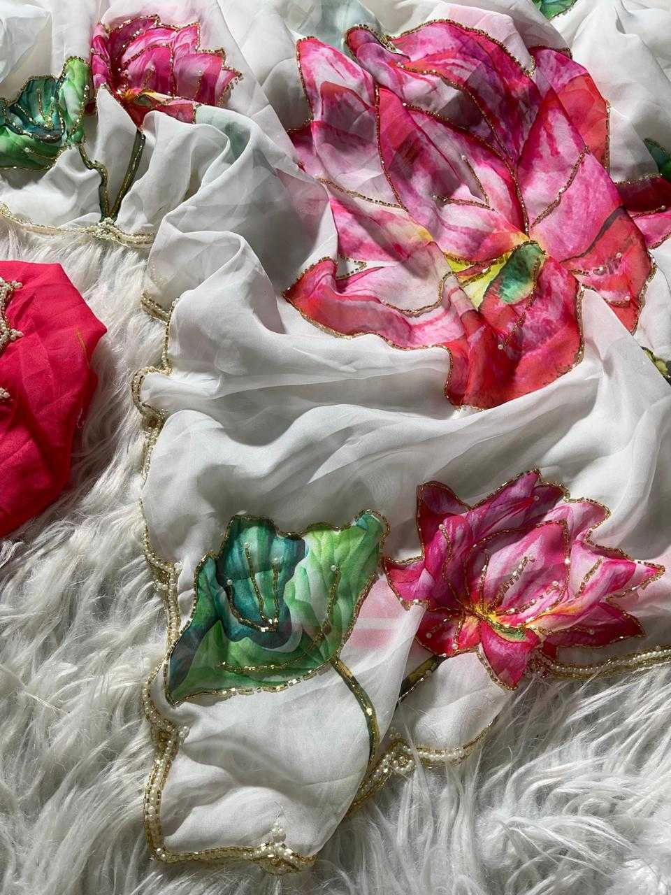 White sheer fabric with large embroidered pink lotus flowers and green leaves, decorated with gold sequins and trim, laid flat on a white faux fur surface.