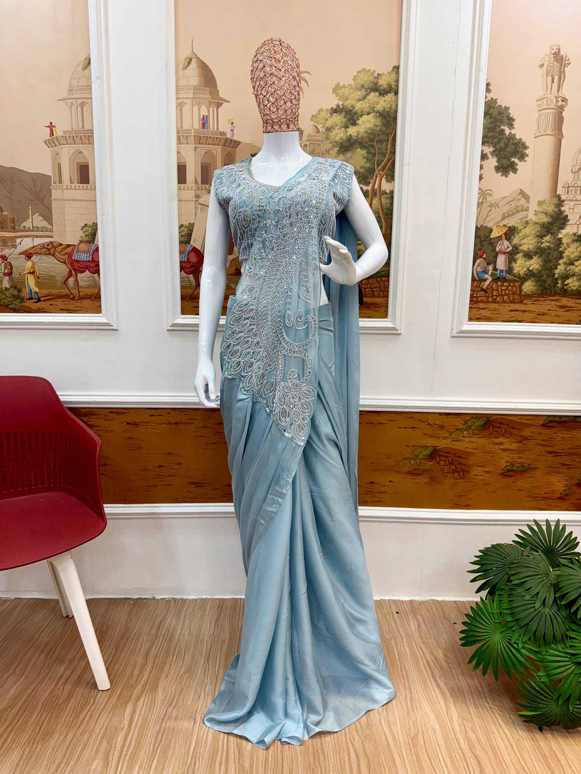 Mannequin wearing a light blue saree with intricate lace detailing in a room with decorative wall art.