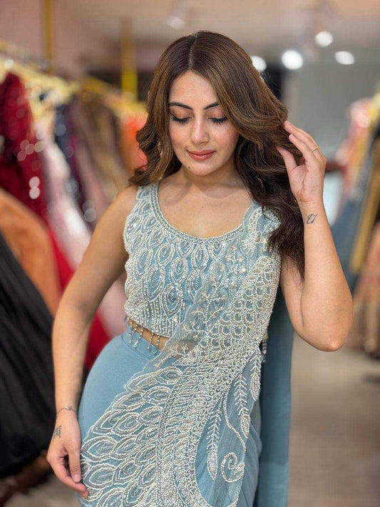 Woman wearing a light blue embroidered saree in a clothing store.