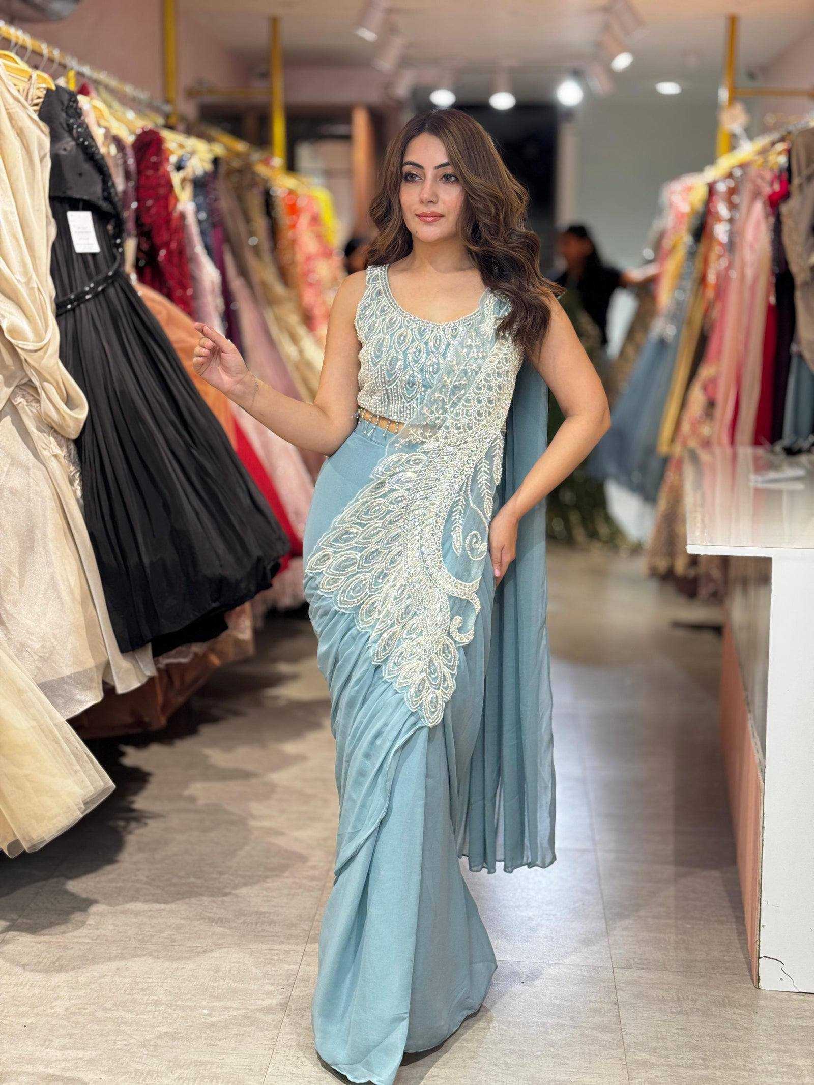 Woman in a light blue saree with white embroidery in a clothing store.