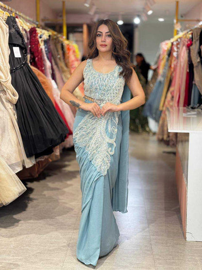 Woman in a light blue saree with white embroidery standing in a clothing store.