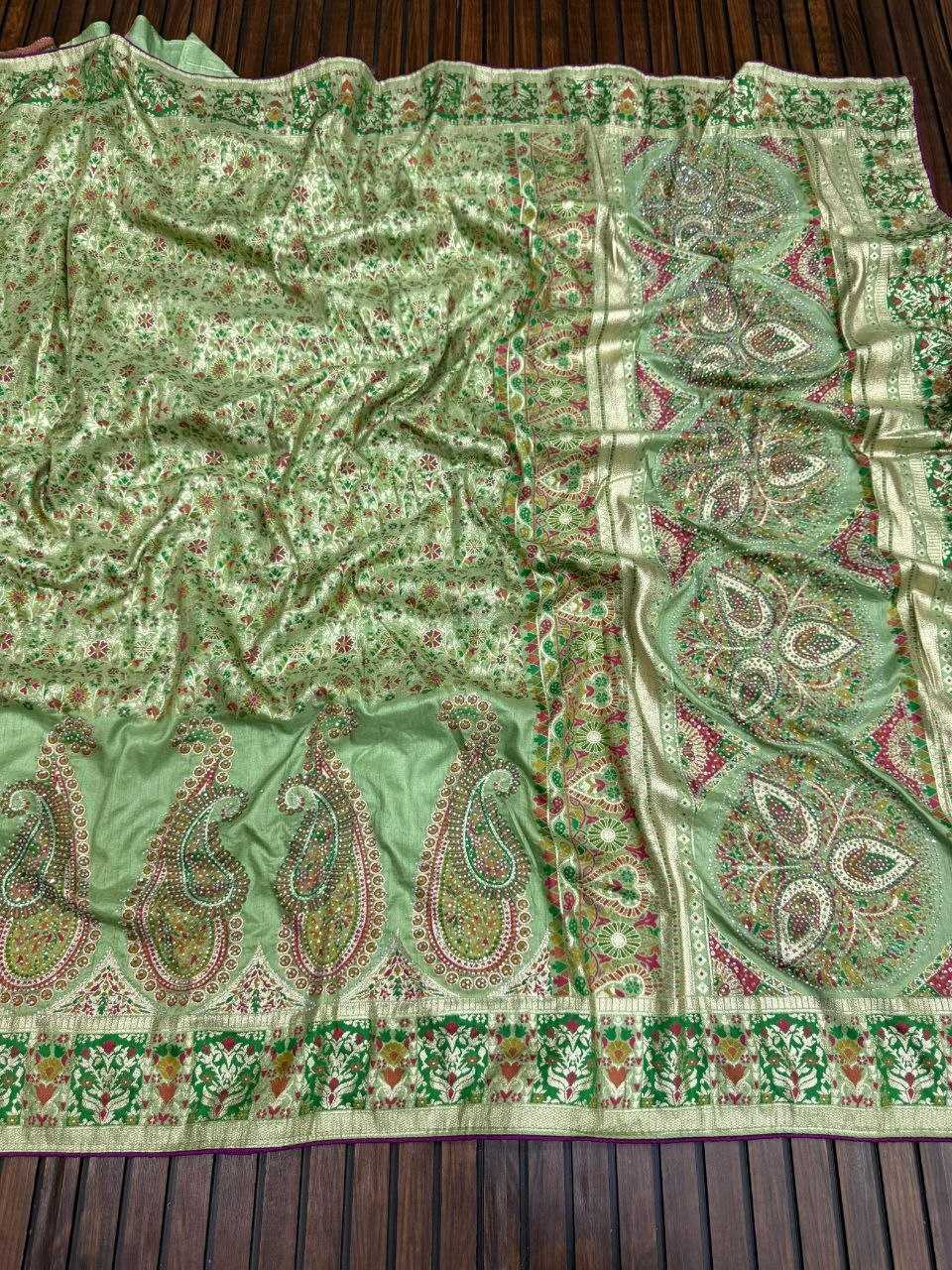 Green patterned fabric with paisley designs on a wooden surface