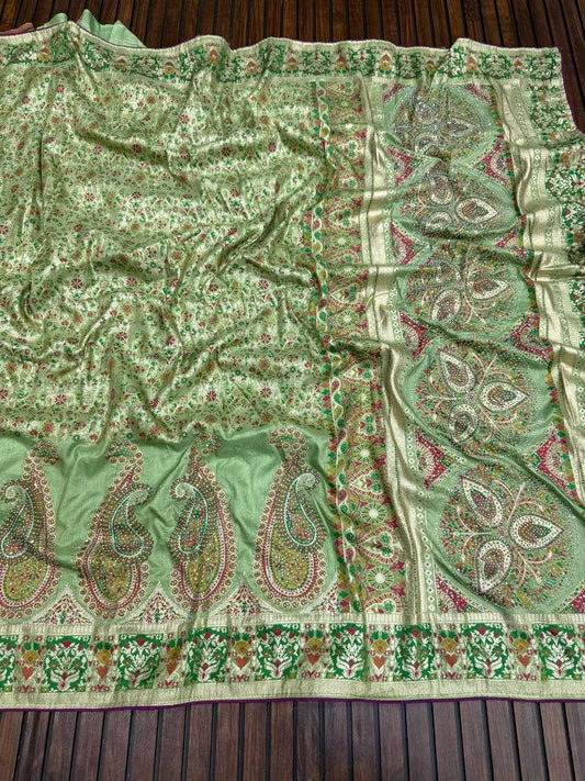 Green patterned fabric with paisley designs on a wooden surface