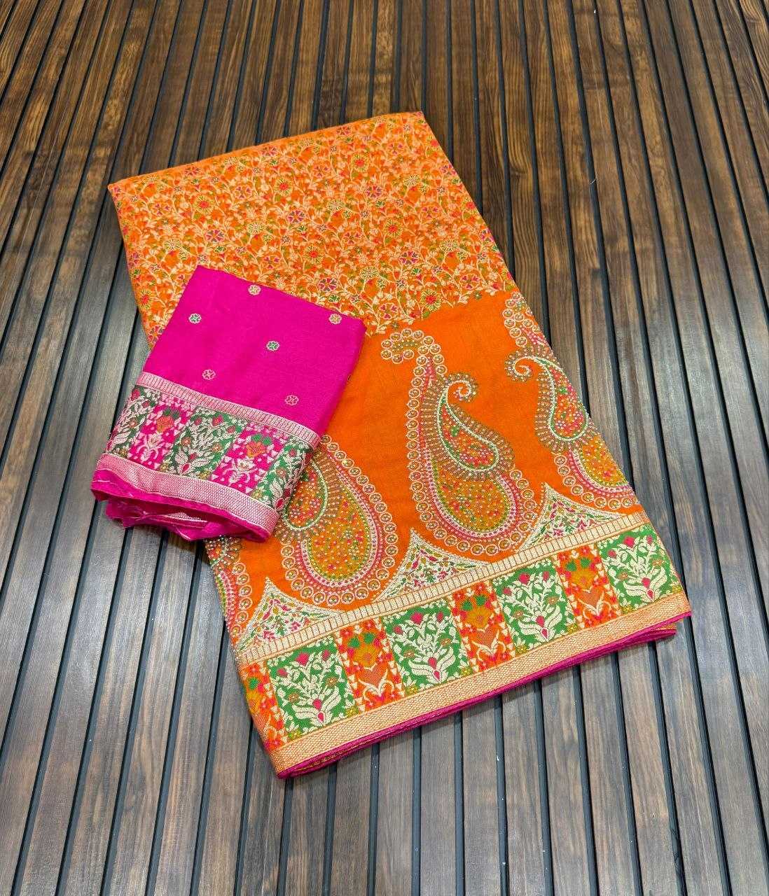 Orange saree with paisley patterns and a pink blouse on a wooden surface