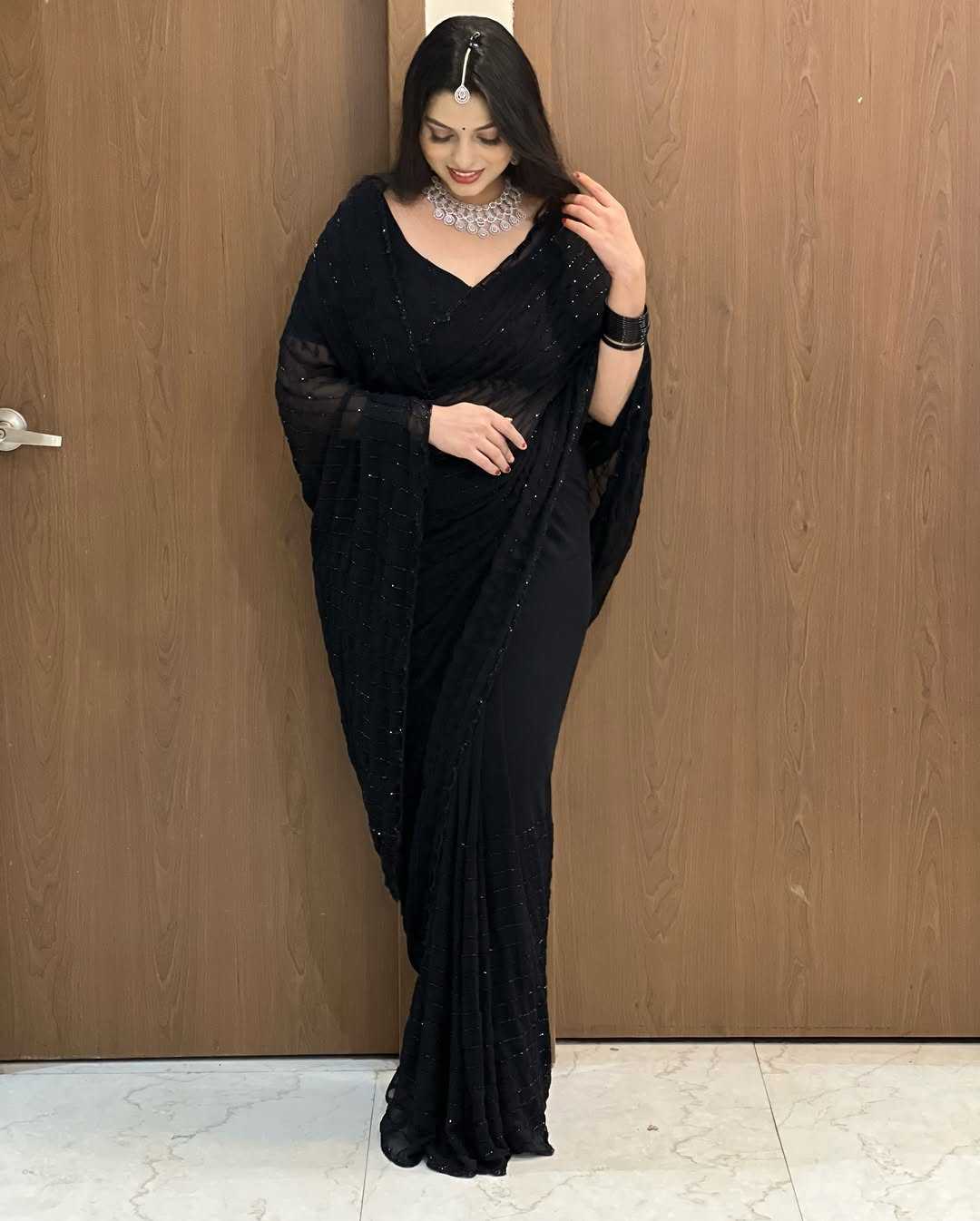 Woman wearing a black saree with a wooden door background