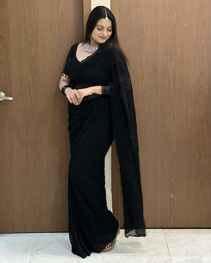Woman wearing a black saree with a plain background