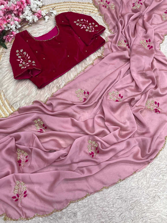 A pink georgette saree with gold and pink floral embroidery, draped elegantly alongside a deep red velvet blouse with matching embroidery, laid out on a white textured rug.