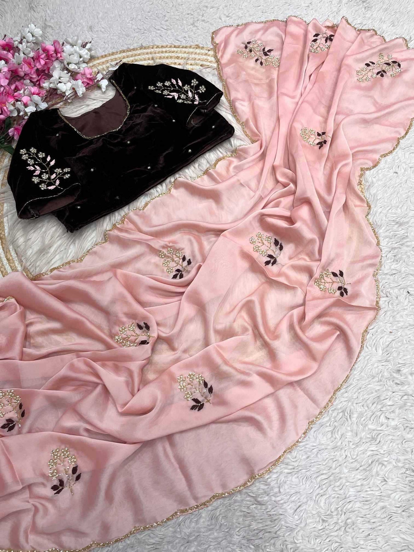 Pink embroidered fabric with a black garment on a textured surface.