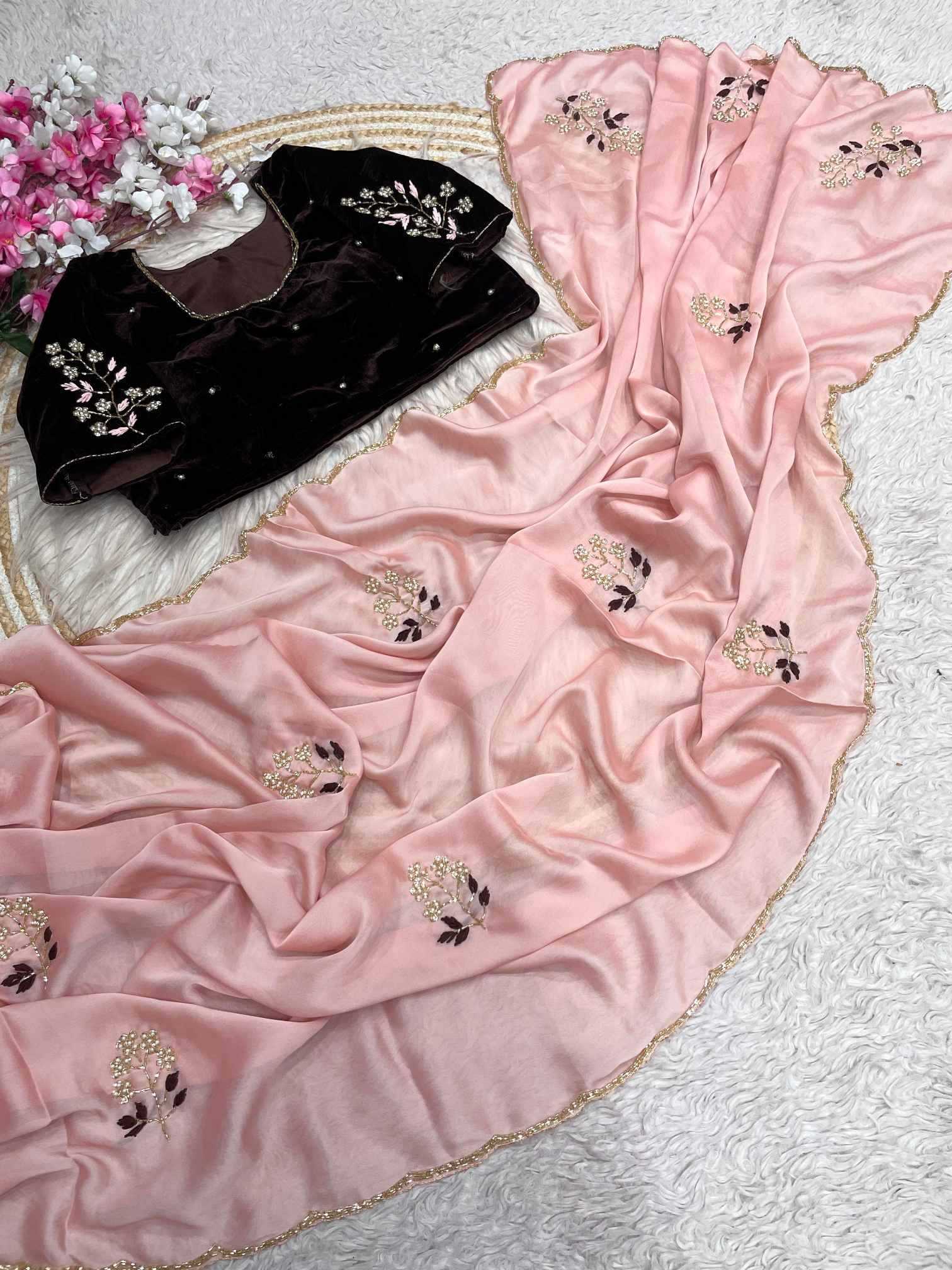 Pink embroidered fabric with a black garment on a textured surface.