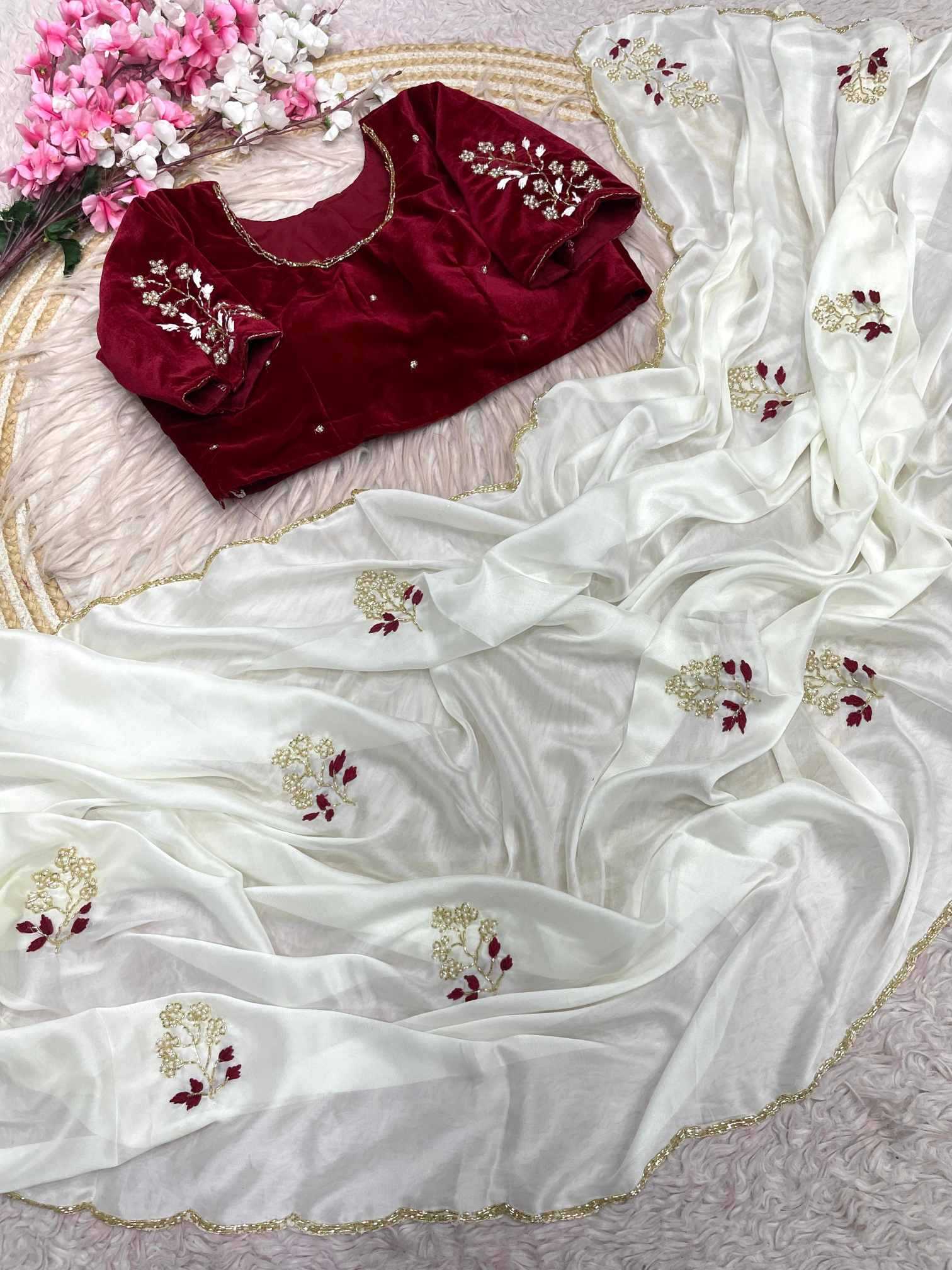 Maroon blouse with white saree featuring floral embroidery on a textured surface.