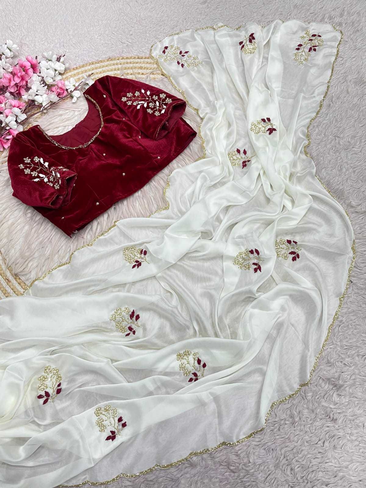 An off-white georgette saree with gold and maroon floral embroidery, displayed alongside a deep red velvet blouse with matching embroidery, arranged on a textured light gray surface.