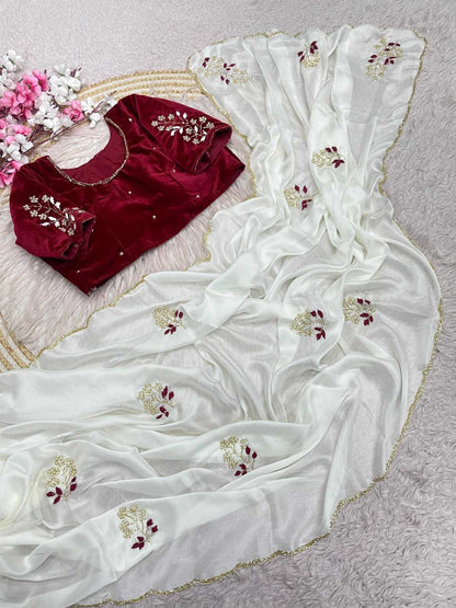 An off-white georgette saree with gold and maroon floral embroidery, displayed alongside a deep red velvet blouse with matching embroidery, arranged on a textured light gray surface.