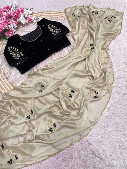 Beige saree with floral embroidery and black blouse on a textured surface.