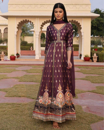 Woman in a traditional embroidered dress standing in a garden with architectural elements in the background
