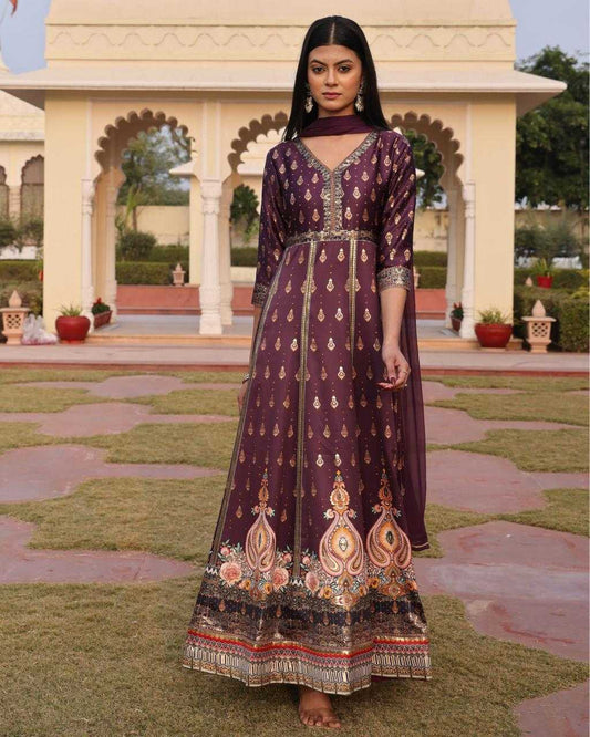 Woman in a traditional embroidered dress standing in a garden with architectural elements in the background