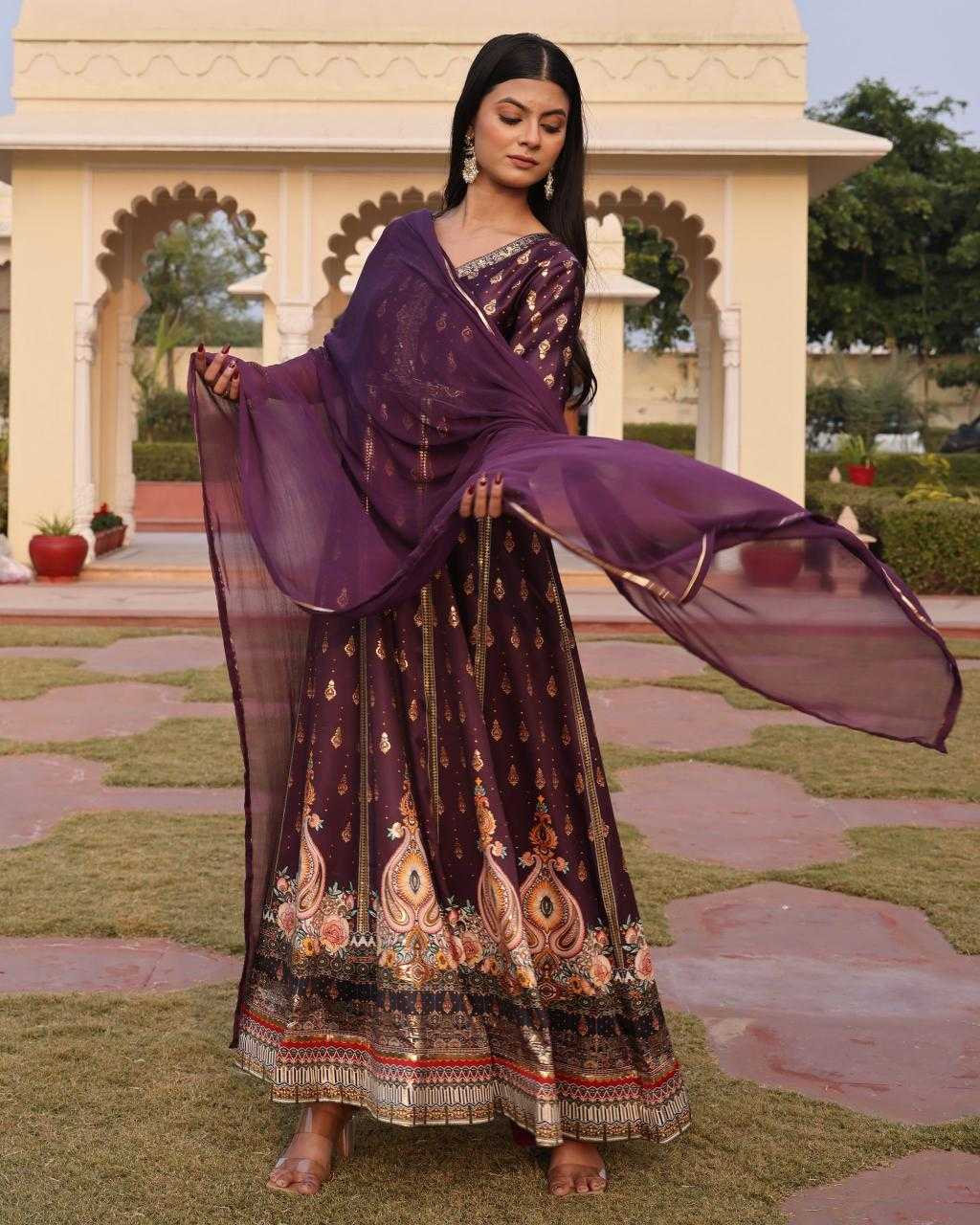 Woman in a traditional outfit with a purple dupatta standing in an outdoor setting.