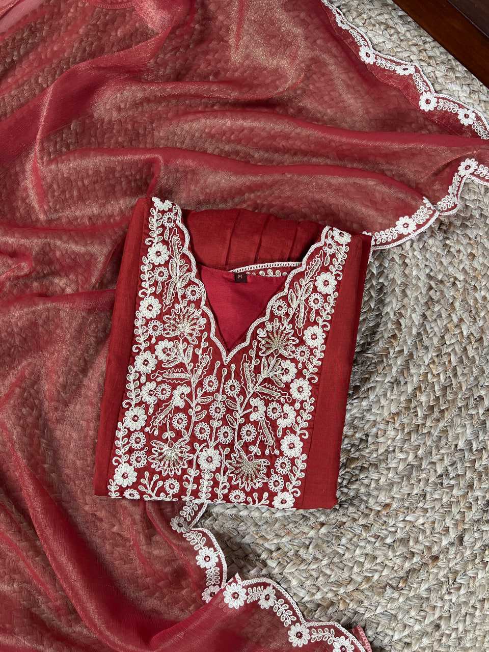 Red garment with white embroidery on a textured surface