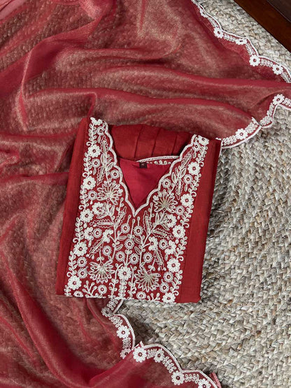 Red garment with white embroidery on a textured surface