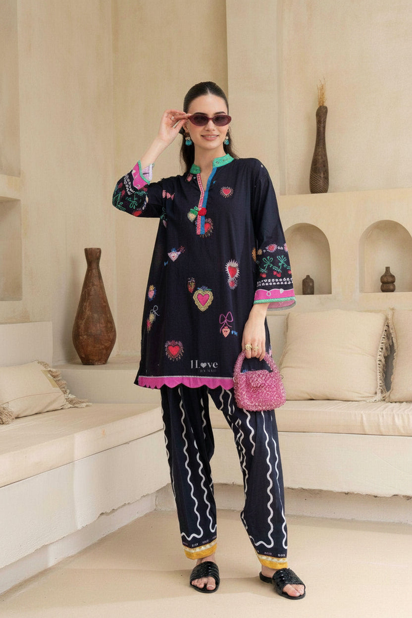 Woman wearing a black embroidered outfit in a living room setting