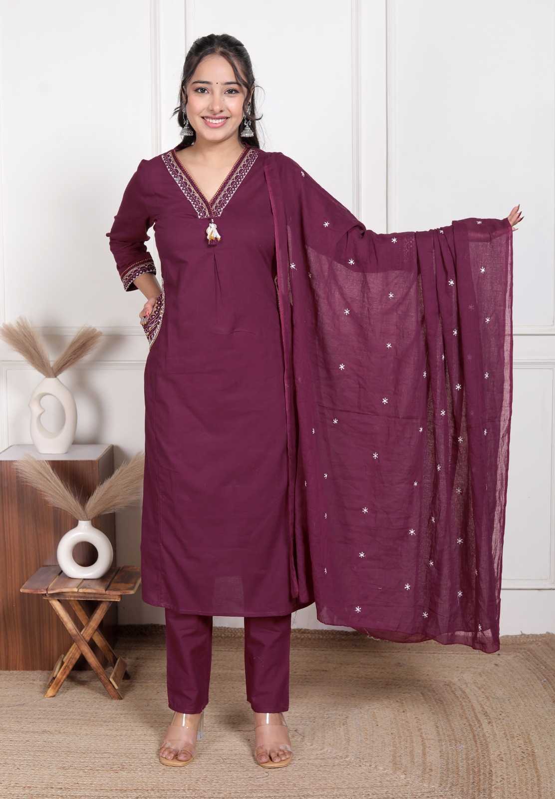 Woman wearing a purple traditional outfit with a matching dupatta in a room setting.
