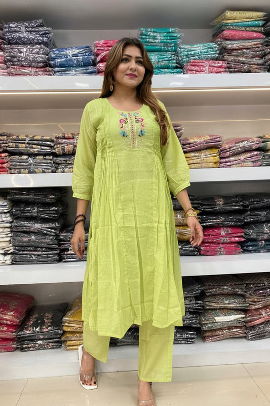 Woman wearing a light green dress with embroidery in a clothing store.