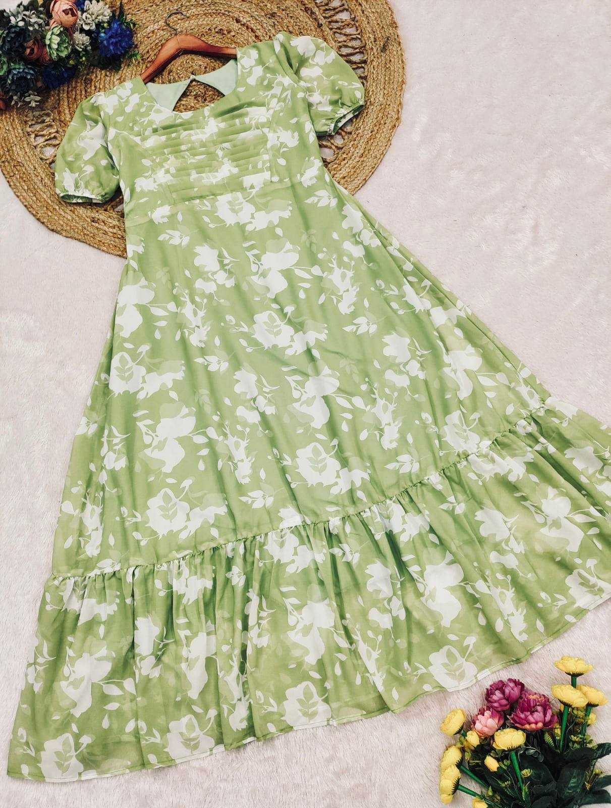 A light green short-sleeve dress with a white floral print, laid flat on a textured white surface with a woven mat and flowers as styling props.
