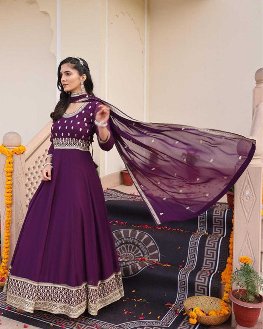 Woman in a purple traditional outfit with a flowing scarf in an indoor setting.