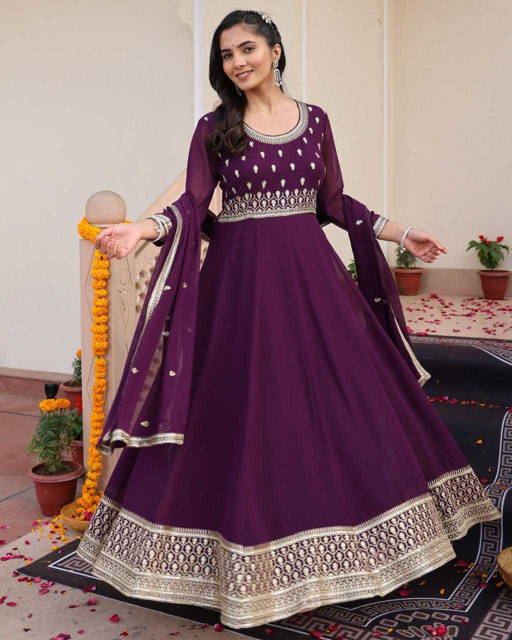 Woman in a purple traditional outfit with intricate designs in an indoor setting.