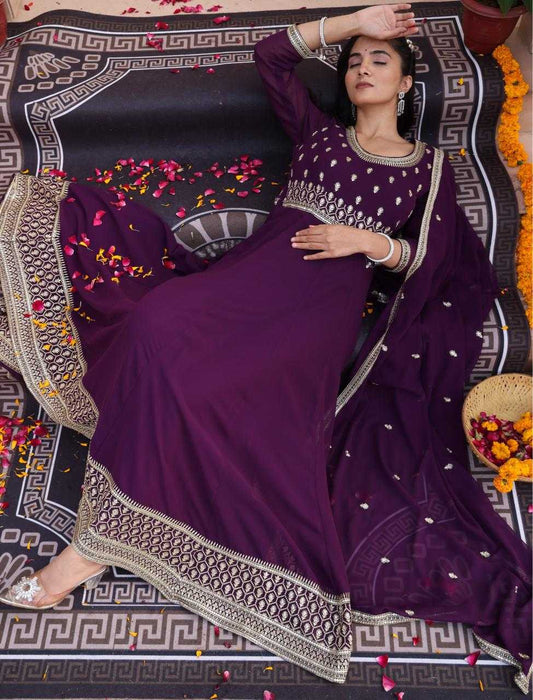 Woman in a purple traditional outfit with intricate designs lying on a decorated floor.